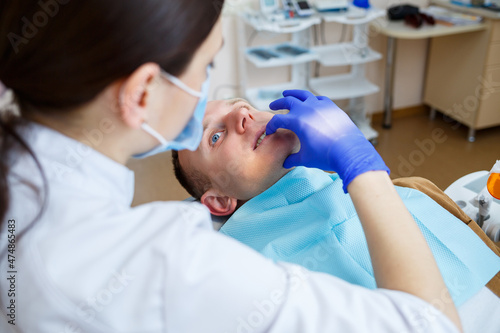 Woman dentist while treating a patient. The doctor makes dental treatment on the teeth of a person in the dentist's chair. Selective focus.