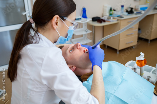 Woman dentist while treating a patient. The doctor makes dental treatment on the teeth of a person in the dentist's chair. Selective focus.