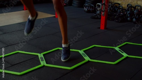 Close-up of female legs practicing cardio intense workout using hex speed rings for ability footwork training, doing high knee walking exercise, improving coordination and quickness indoors.