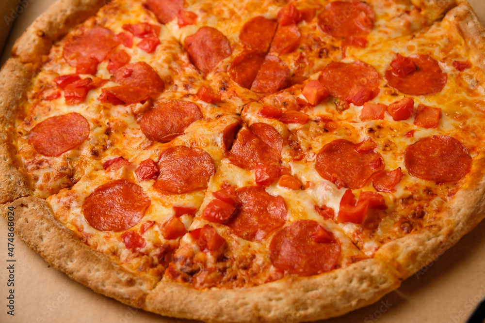 Fresh pepperoni pizza in a box with salami slices delivered home. Fast food delivery from restaurant.