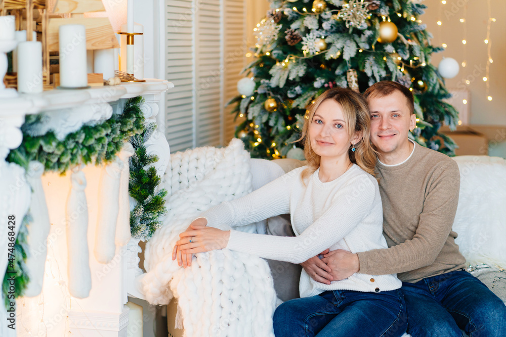 an attractive blonde woman and and man in a sweater on a sofa by the fireplace. an attractive blonde woman and and man in a sweater on a sofa by the fireplace.