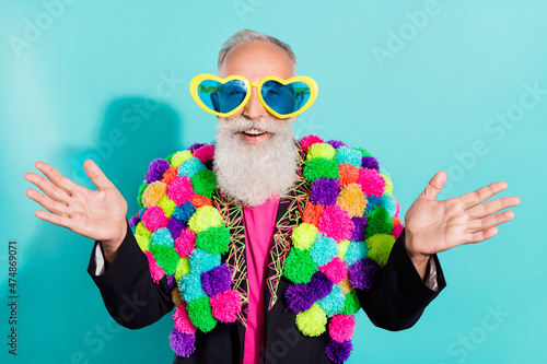 Photo of charming impressed mature guy dressed creative pom-pom jacket eyewear smiling isolated turquoise color background