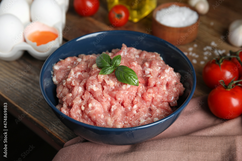 Raw chicken minced meat with basil and ingredients on wooden table, closeup Raw chicken minced meat with basil and ingredients on wooden table, closeup