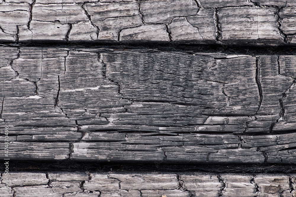 Φωτογραφία Textured monochrome background of rough burnt wood of dark color with cracks in