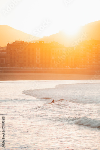 Silhouette of a lonely surfer riding a wave during sunset in San Sebastian beach