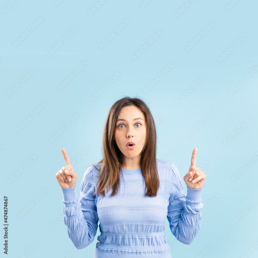 Studio shot of astonished woman, points upstairs, for your advertising content, against on blue background. Studio shot of astonished woman, points upstairs, for your advertising content, against on blue background.