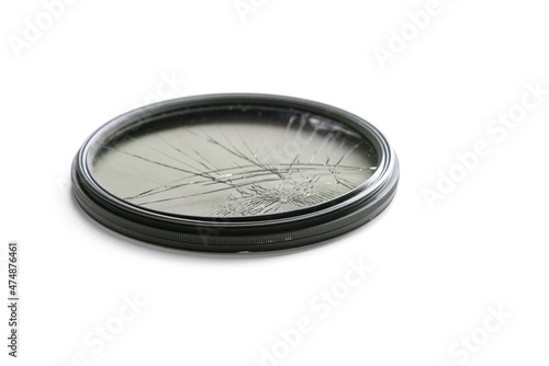 Closeup high angle studio shot of black circular polarizer filter with cracked glass, isolated on white background. Concept for photo gear damage, accident, repair or insurance.