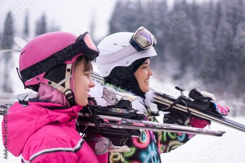 Portrait of 2 beautiful teenager girl and woman with ski and ski suit in winter mountain