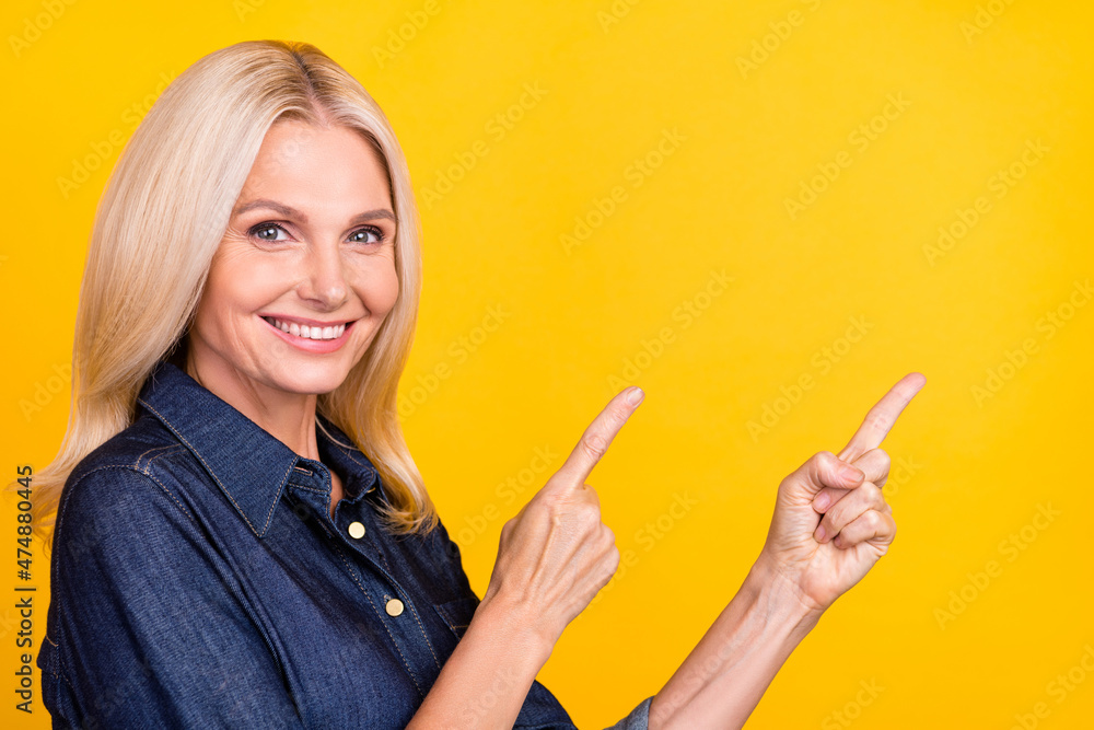 Photo of cute shiny lady pensioner dressed denim outfit pointing empty space isolated yellow color background Photo of cute shiny lady pensioner dressed denim outfit pointing empty space isolated yellow color background