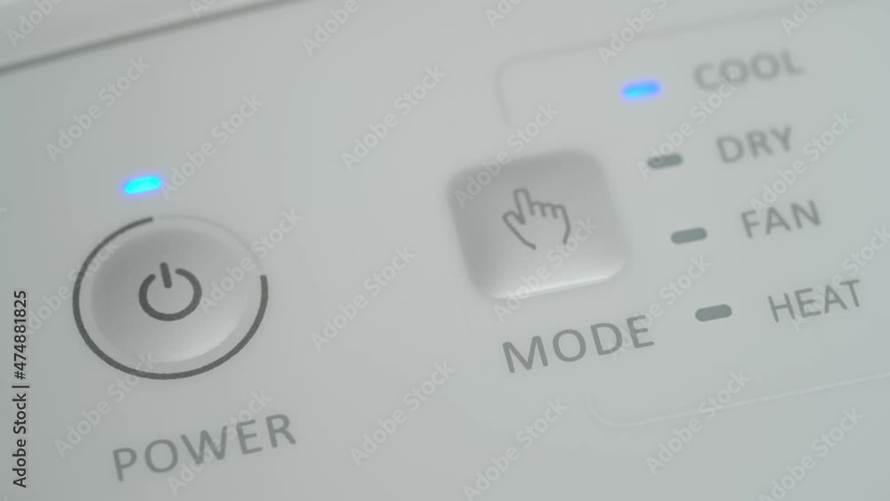 The person presses the start button on the mobile air conditioner to cool the room. Close-up. The person presses the start button on the mobile air conditioner to cool the room. Close-up.