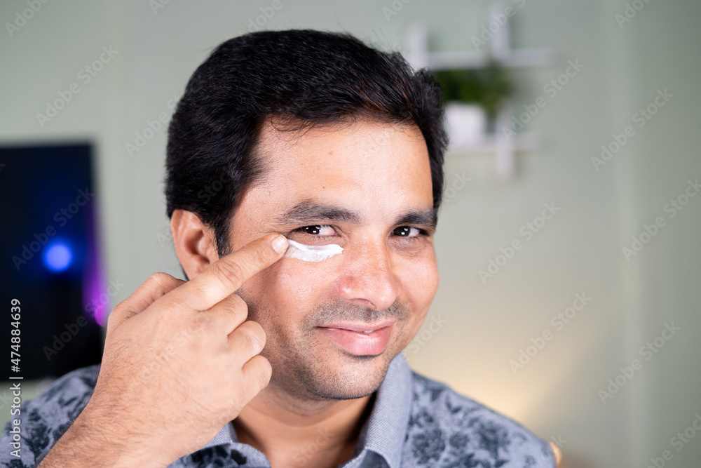 Close up shot of young man applying cream to dark circle under eyes - concept of fairness and Skin care protection. Close up shot of young man applying cream to dark circle under eyes - concept of fairness and Skin care protection.