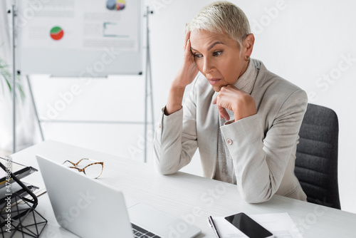 surprised senior businesswoman looking at laptop on desk