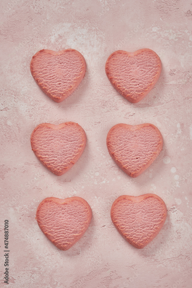 Fototapeta premium Valentine day decorated heart shaped cookies on pink background, top view