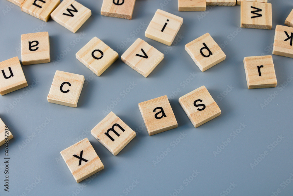 Scattered wooden tiles with letters with visible words - covid, xmas isolated on grey background Scattered wooden tiles with letters with visible words - covid, xmas isolated on grey background