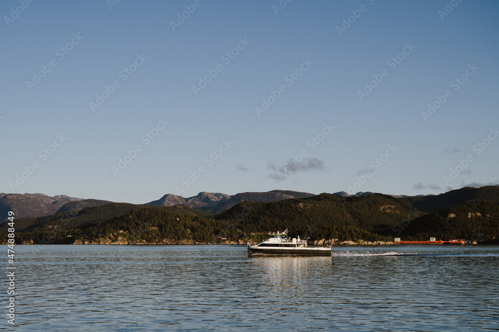 Landscape of hilly area of island in Lusefjord. Boat sails along the fjord. Tourism in Norway. Beautiful nature on sunny day.