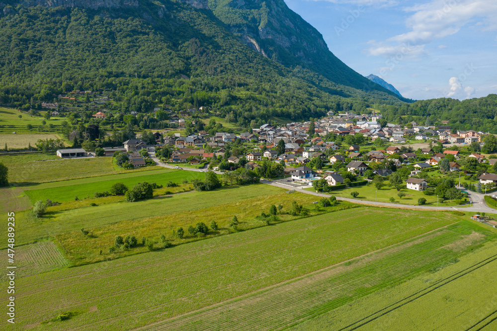 The town of Gresy sur Isere at the foot of the mountain and wheat fields in Europe, France, Isere, the Alps in summer on a sunny day.