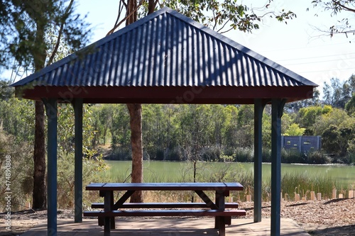Outdoor picnic shelter with table and seats in suburban wetlands area on a sunny summer day