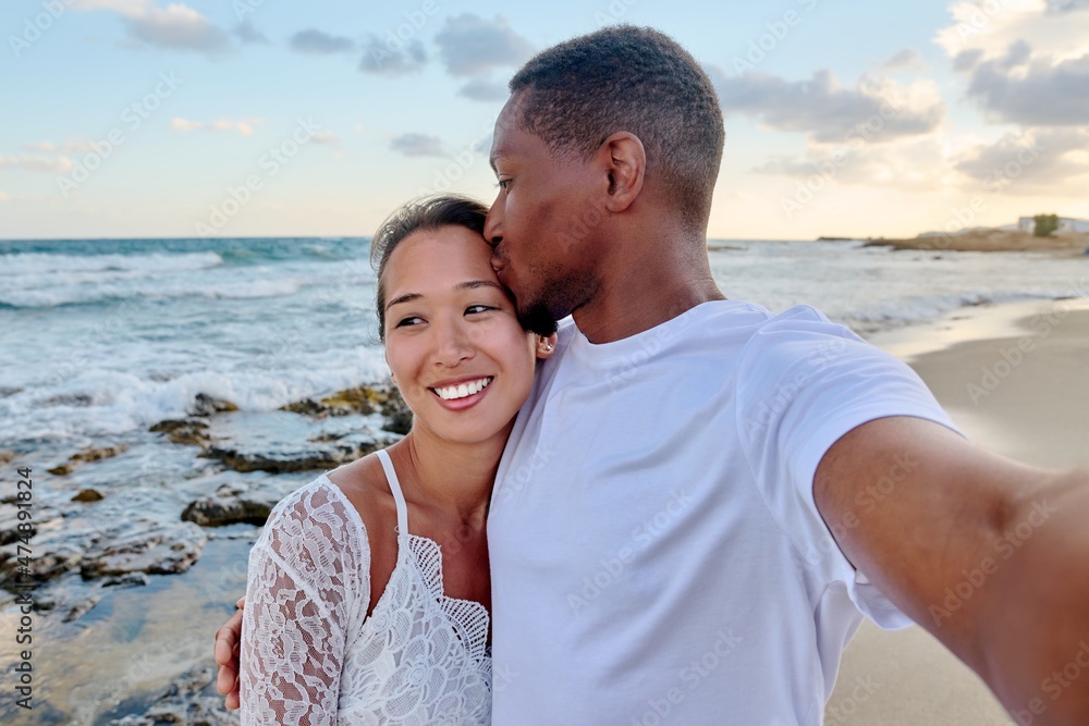 Happy couple in love kissing taking selfie together on smartphone, on beach Happy couple in love kissing taking selfie together on smartphone, on beach