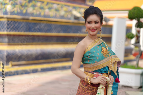 Portrait Asian women smiling and wearing Thai national costumes are inside temples to worship Buddha with flower garlands on important religious days for Thai people.