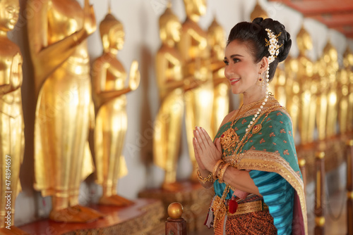 Portrait Asian women smiling and wearing Thai national costumes are inside temples to worship Buddha with flower garlands on important religious days for Thai people. photo