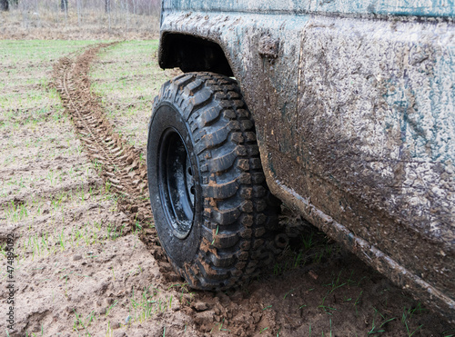Dirty jeep wheel close up. Wheel mark on the ground. © Dzmitry