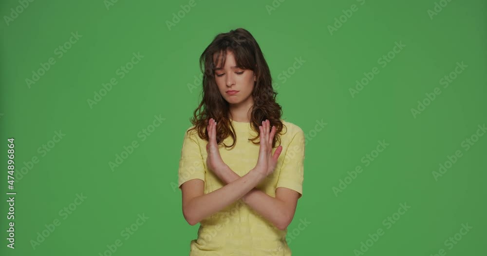 Serious young girl showing stop gesture, protesting, deny, warning, prohibiting on chroma key green studio background Serious young girl showing stop gesture, protesting, deny, warning, prohibiting on chroma key green studio background