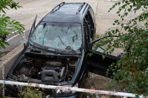 Black car wreck abandoned overgrown open trunk engine