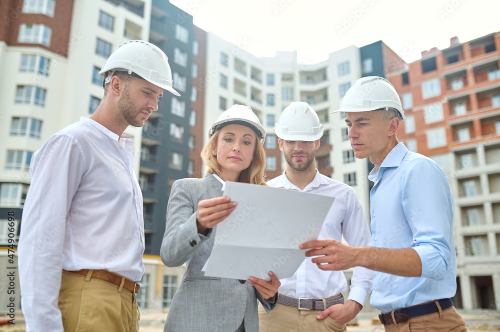 Woman and men looking at drawing at construction site Woman and men looking at drawing at construction site