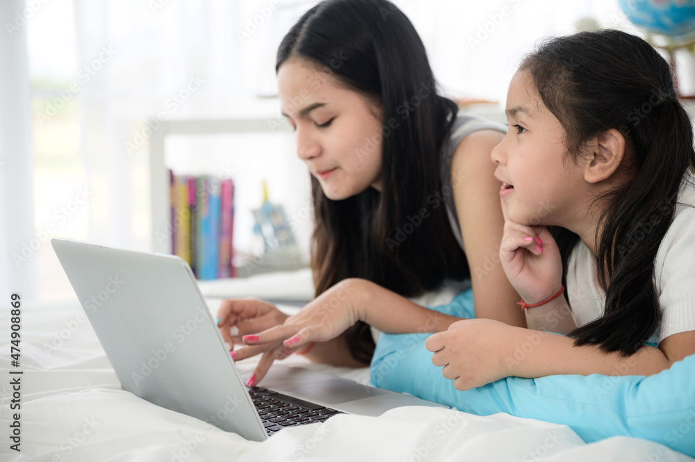 child girl person 2 sisters watching media and learning on laptop, online communication at home child girl person 2 sisters watching media and learning on laptop, online communication at home