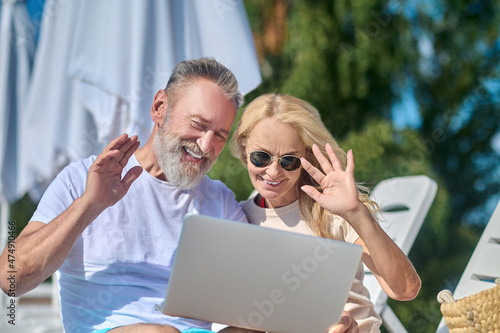 Mature couple having a video call and waving their hands