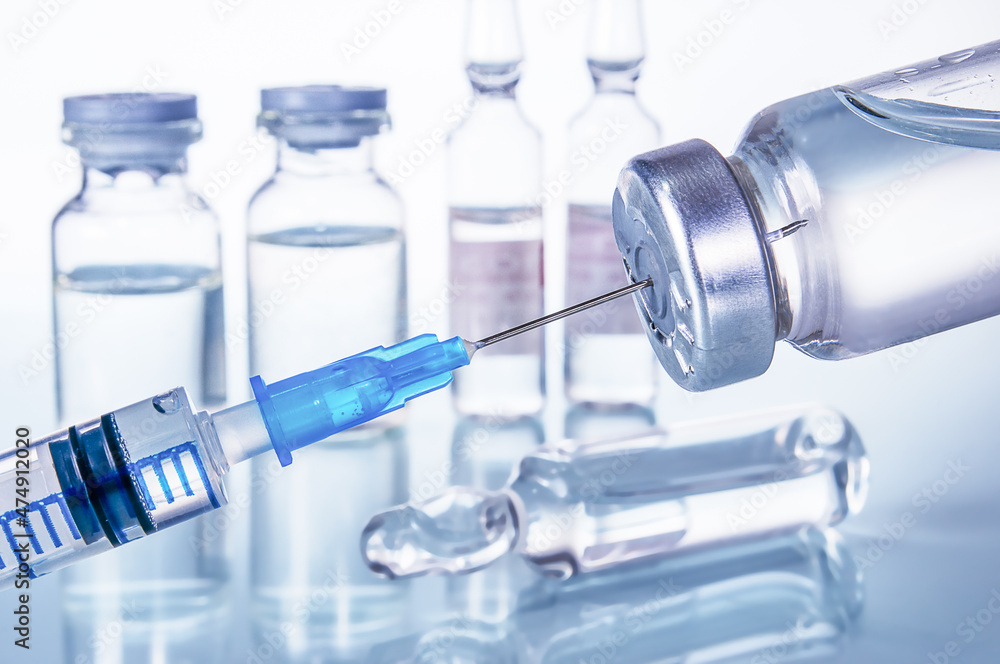 syringe and diferent kind of ampoules and vials close-up on white background with reflection syringe and diferent kind of ampoules and vials close-up on white background with reflection