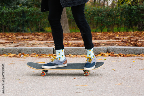 Crop person in sneakers on skateboard on asphalt road