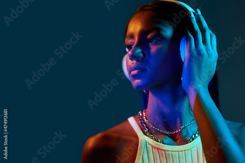 Black Brazilian woman listening to music under fluorescent light