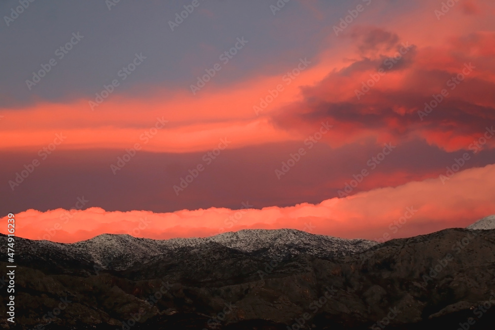 Mountain peaks covered in snow and pink clouds in the sky. Beautiful winter sunset in Croatia. Mountain peaks covered in snow and pink clouds in the sky. Beautiful winter sunset in Croatia.