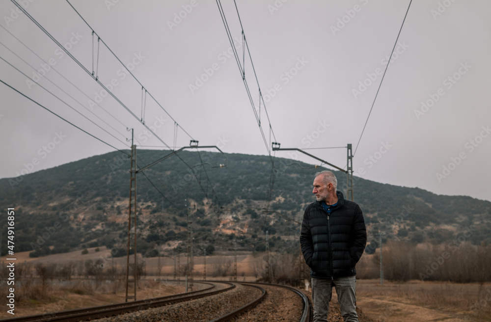 Obraz premium Adult man in warm clothing with railway in countryside. Shot in Castilla la Mancha, Spain