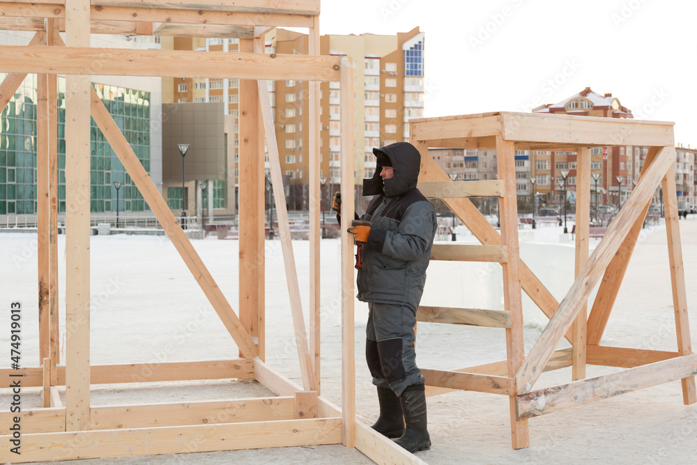 Fototapeta premium Worker assembling the frame of a wooden slide