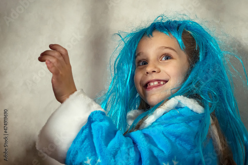 Smiling girl in a blue wig and snow maiden costume on a gray background. Close-up. photo