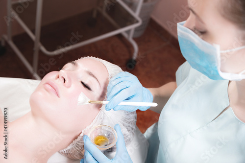 face of a young woman close-up lying down cosmetic procedure is performed applying a rejuvenating mask.