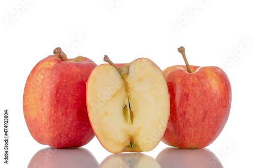 One half and two whole organic red apples, close-up, isolated on white.