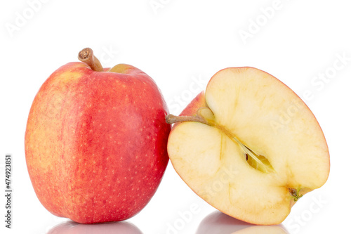 One half and one whole organic red apples, close-up, isolated on white.
