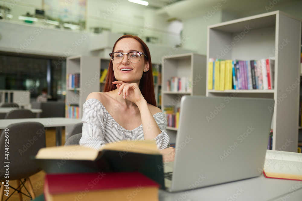 Woman at table with laptop looking to side Woman at table with laptop looking to side