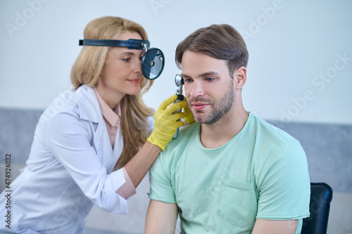Canvas Print Woman examining mans ear through frontal reflector