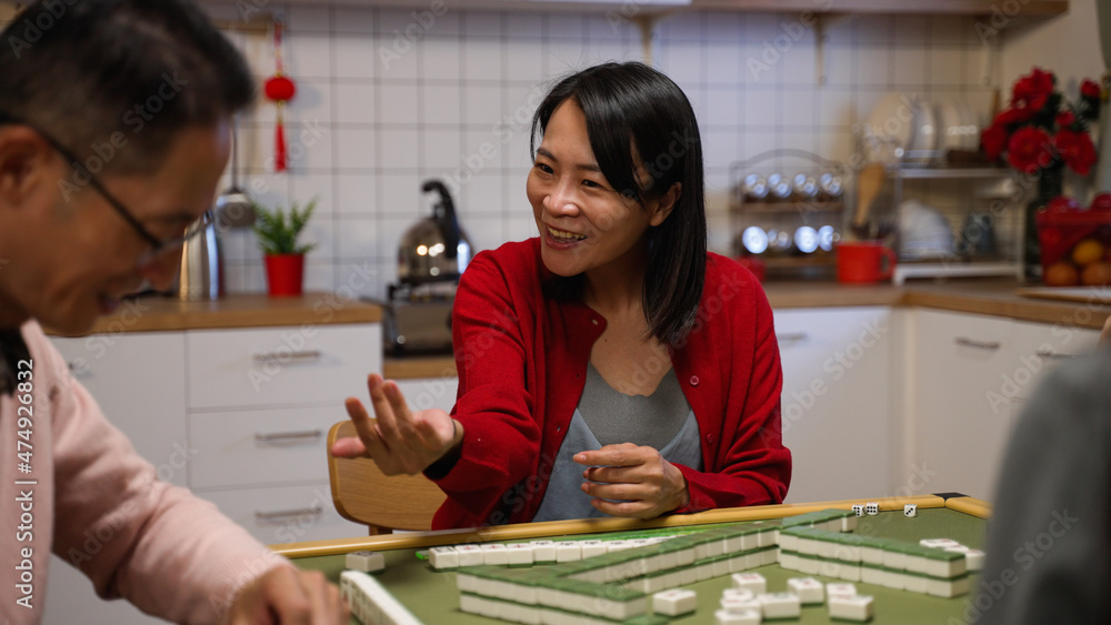 mother winning by self draw smiling with embarrassment as she fails to lay her complete set on table while playing mahjong in the evening at home during spring festival