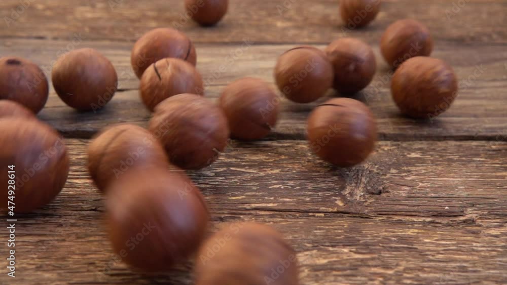 Macadamia nuts in shells fall on the old wooden vintage board. Slow motion. Macadamia nuts in shells fall on the old wooden vintage board. Slow motion.