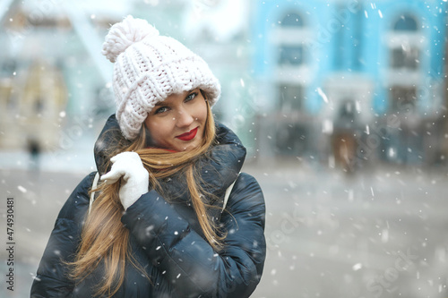 Merry blond lady walking at the city with snowflakes