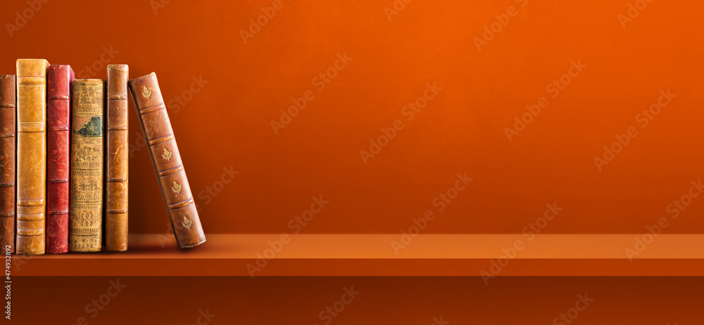 Row of old books on orange shelf. Background banner Row of old books on orange shelf. Background banner