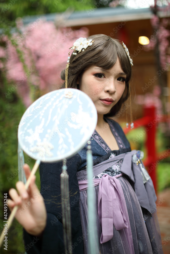 Naklejka premium Beautiful young woman with dark blue Chinese lolita dress with Chinese garden