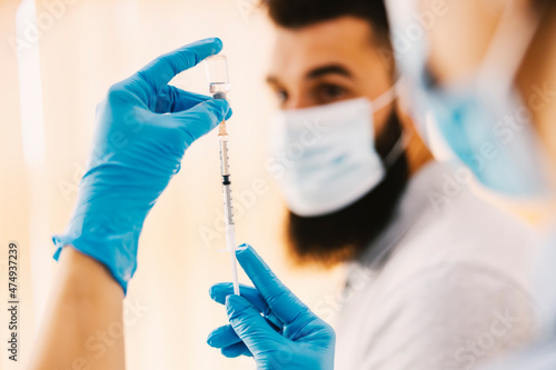 Covid 19 vaccine and health care. Close up of nurse's hands holding a syringe and bottle with covid 19 vaccine and preparing it for a patient.