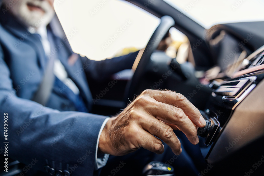 Close up of senior businessman's hand on the radio button. The senior businessman is turning on the music.