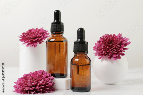 A mock-up of an empty glass dropper bottle made of brown glass stands on a white podium and a white background. Skin care serum, banner or template. The concept of a natural cosmetic product.Copyspace